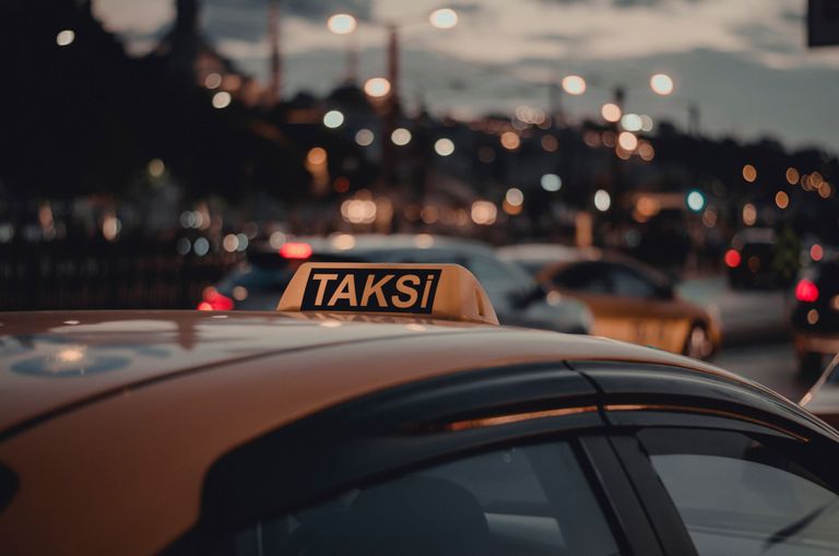 Close-up of a taxi with a 'Taksi' sign on a busy Istanbul street at night with bokeh lights.